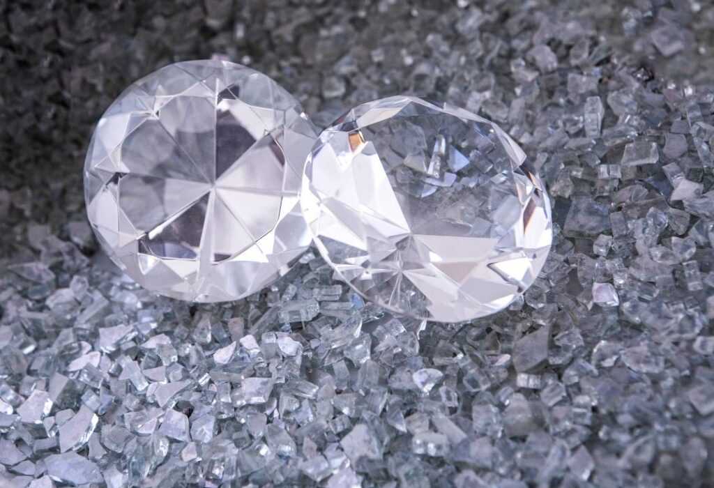 Two diamonds sitting on top of a pile of crushed glass photo